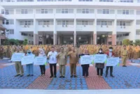 Keterangan Foto: secara simbolis santunan jaminan kematian senilai Rp. 42.000.000,- dan jaminan kecelakaan kerja senilai Rp. 1.167.000,- kepada perwakilan keluarga Tenaga Harian Lepas (THL) di Lingkup Pemerintah Kota Tangerang saat apel pagi, Senin (24/07).